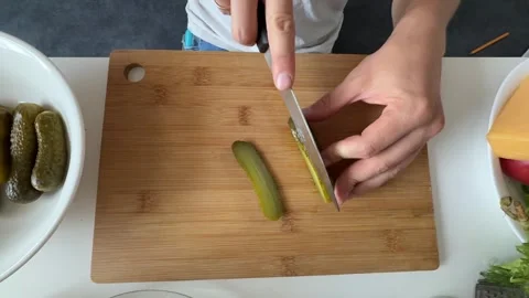 Close up male hands slicing pickled cucumber on wooden board for salad dressing. Stock Footage 337338819