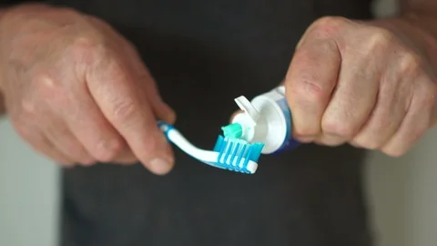 Close up of an male hands squeezes toothpaste into a toothbrush. Focusing on Stock Footage 121053354
