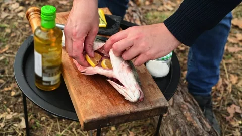 Close up of male hands stuffing fish with lemon slices before cooking 库存影片 334681006