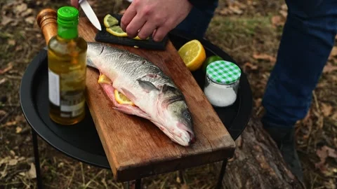Close up of male hands stuffing fish with lemon slices before cooking Stockbeeldmateriaal 334681009