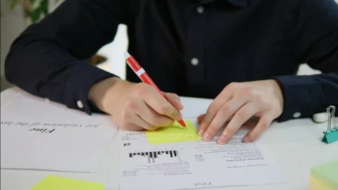 Close up of male hands at table with fine and sticky note sticking to fine and Stock Footage 313588535