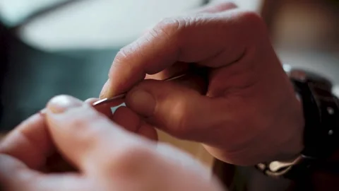 Close-up of male hands threading a needle and tying a knot in workshop Stockbeeldmateriaal 146347304