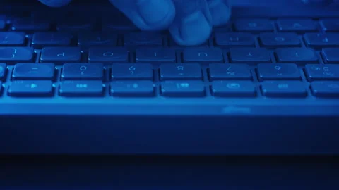 Close-up male hands typing on keyboard under blue ambient lighting Видео 340926632