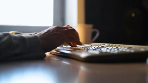 Close-up of male hands typing on white keyboard while sitting at table, indoors. Stockbeeldmateriaal 197997639