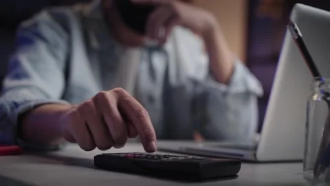 Close up male hands using calculator in front of laptop at night. Unrecognizable Stock Footage 255668355