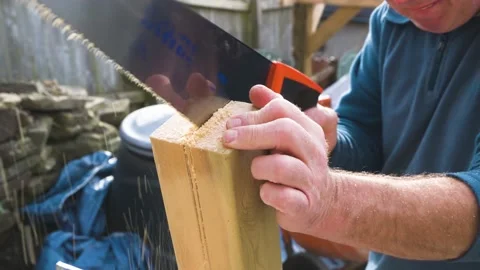 Close up of Male hands using hand saw to cut through hand rail post for garden Stock Footage 142709193