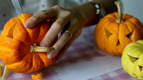 Close-up of male hands using a knife to cut a scary face out of a pumpkin for Video stock 272461424