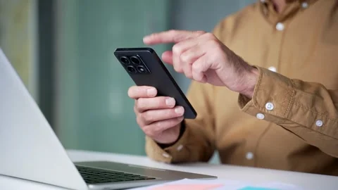 Close-up of male hands using a smartphone while working at a desk in a modern  Stock Footage 342019596