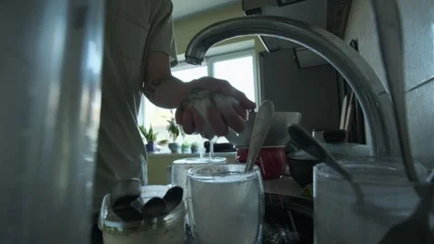 Close-up of male hands using a sponge and soap to wash dirty plates at home Stock Footage 309990789