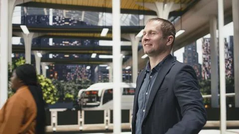 Close up of male passenger smiling while walking in bus station, holding trolley Photos