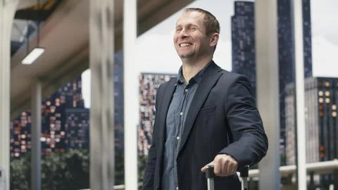 Close up of male passenger smiling while walking in bus station, holding trolley Photos