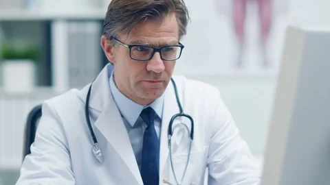 Close-up of a Male Senior Doctor Working at His Desk on a Personal Computer.  Stock Footage