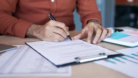 Close up of a male's hand signing documents at a desk at a workplace Stock Footage 305655456