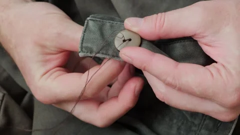 Close-up of male's hands sewing plastic button to cloth. Stock Footage 329767756