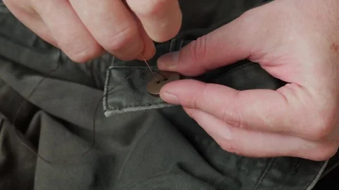 Close-up of male's hands sewing plastic button to cloth. Stock Footage 330328716