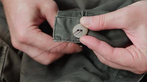 Close-up of male's hands sewing plastic button to cloth. Vídeo Stock 331423654