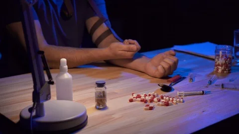 Close up man addict in a dark room at the table enters the drugs Video stock 106363771