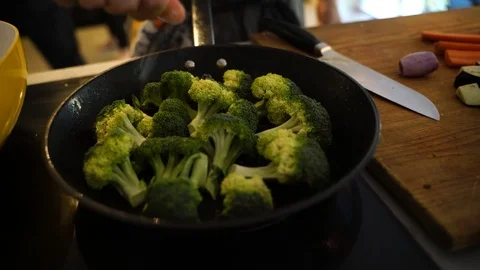 Close-up of man adding salt in broccoli on frying pan Stock Footage 114883422
