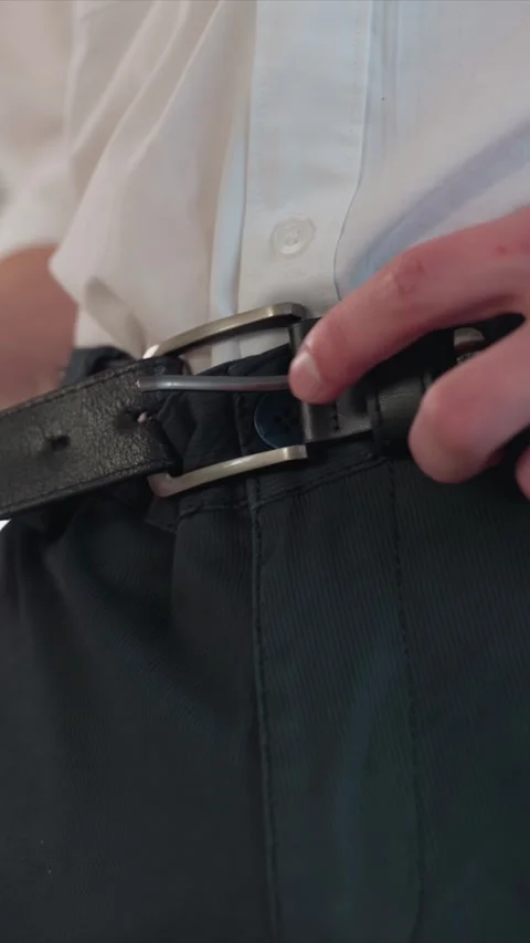 Close up of man adjusting black leather belt with silver buckle over white shirt Stock Footage 344412199