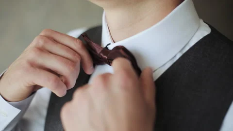 Close-up of man adjusting bow tie. Attractive man epicly adjusts bow tie on suit Stock Footage 196003045
