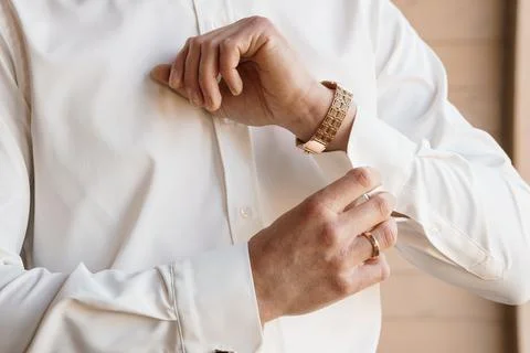 Close up of man adjusting cuff of white formal dress shirt wearing gold wat.. Stock Photos