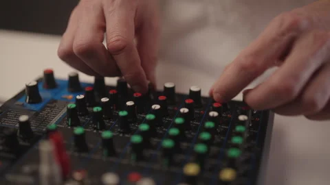 Close-up of man adjusting faders and knobs on sound mixer, creating music and Stockbeeldmateriaal 325715322