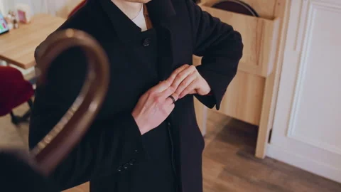 Close up of man adjusting his black coat buttons with visible fabric texture in Stock Footage 344876772