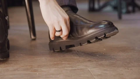 Close up of man adjusting his black leather ankle boot with zipper detail on Stock Footage 345732683
