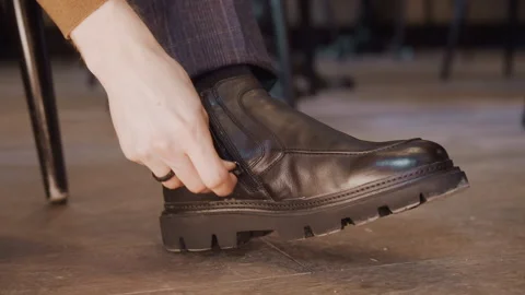 Close up of man adjusting zipper on his black leather ankle boot with shoe Stock Footage 344872666