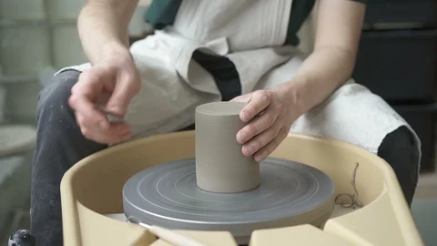 Close-up of man in apron on potter's wheel is treating product with metal tool. Stock Footage 88483677