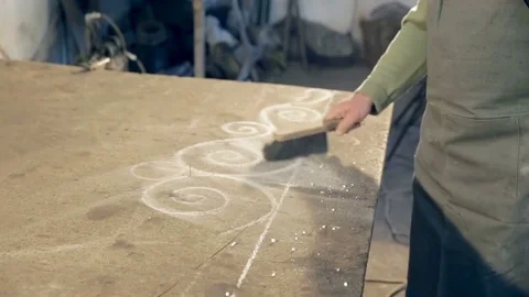 Close-up man in apron sweeping dust from the table Stockbeeldmateriaal 77025482