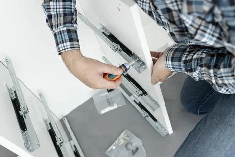 Close up of a Man Assembling a drawer slider Furniture using a screwdriver... Stock Photos