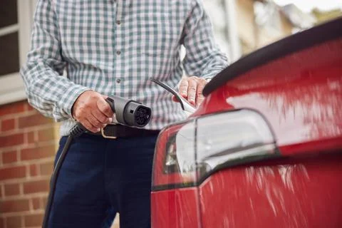 Close Up Of Man Attaching Charging Cable To Environmentally Friendly Zero Emi Stock Photos