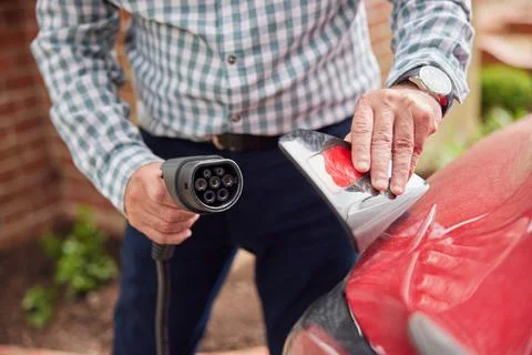 Close Up Of Man Attaching Charging Cable To Environmentally Friendly Zero Emi Foto stock
