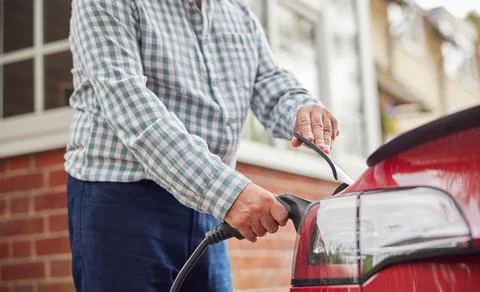 Close Up Of Man Attaching Charging Cable To Environmentally Friendly Zero Emi Stock Photos
