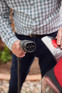 Close Up Of Man Attaching Charging Cable To Environmentally Friendly Zero Emi Stock Photos