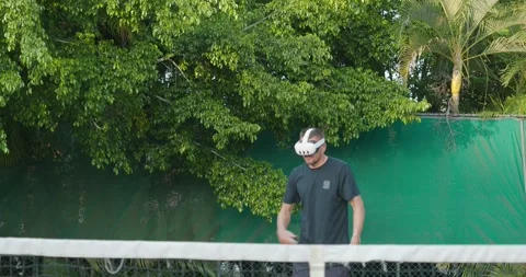 Close-up of man in augmented virtual reality headset plays tennis outside. Stock Footage 269987260