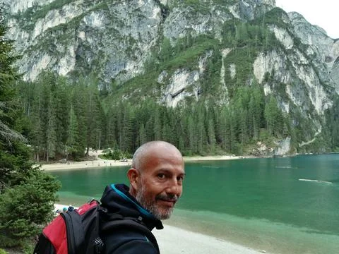 Close-up of man with backpack on his shoulder at Lake Braies with mountains in t Stock Photos