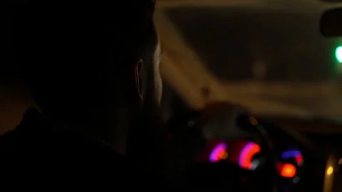 Close-up of a man with a beard drives a car at night against the background of Stock Footage 147624938