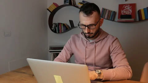 Close-up, man with beard sitting working with laptop from home. Dolly shot. Stock Footage 170963033