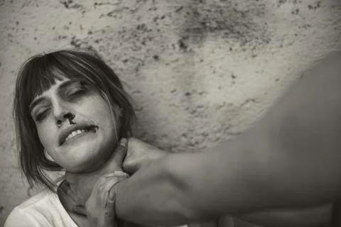 Close-up of a man from behind, hitting with a crying woman to a dirty wall Stock Photos