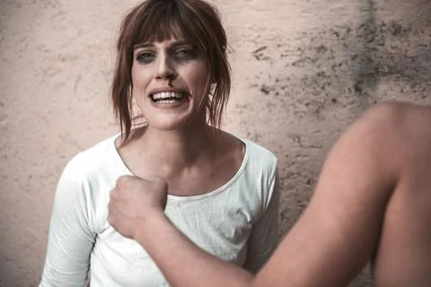 Close-up of a man from behind, hitting with a crying woman to a dirty wall Stock Photos