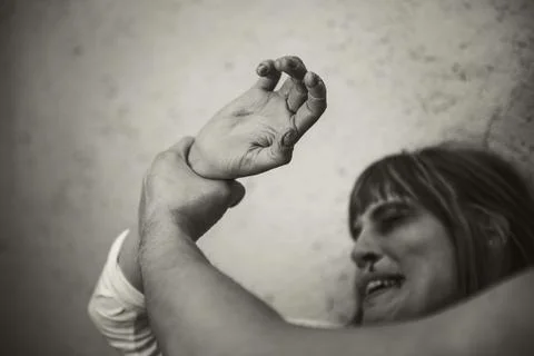Close-up of a man from behind, hitting with a crying woman to a dirty wall 스톡 사진