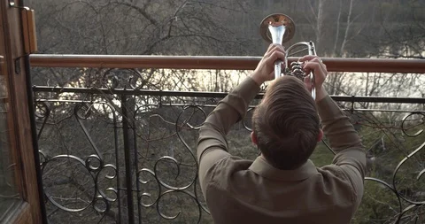 Close-up of a man from behind playing on his balcony on a trumpet . Stock Footage 130137057