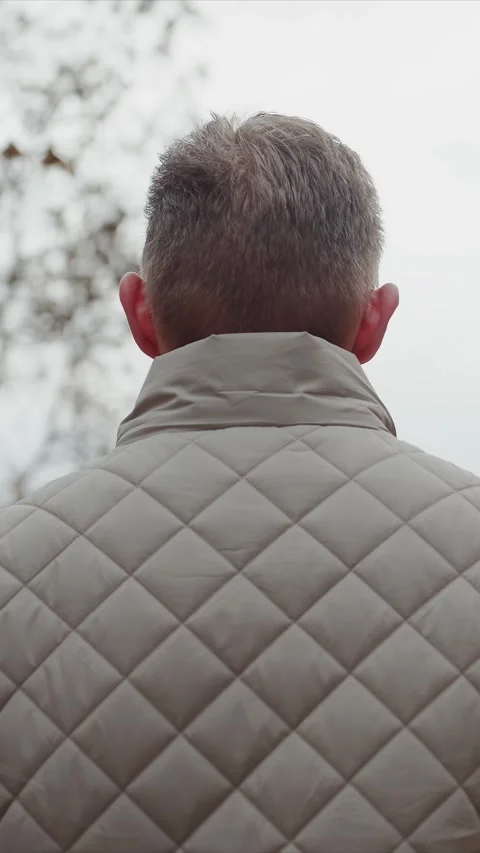 Close up of man in beige quilted vest standing outdoors under overcast winter Stock Footage 342732166