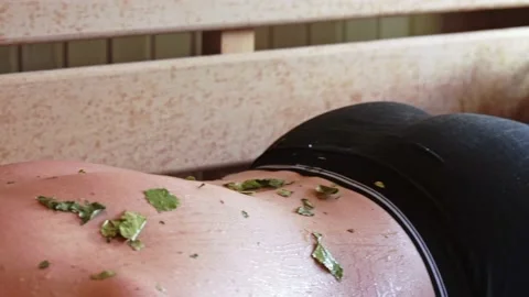 Close-up of a man being beaten on the back steamed with a juniper broom in the Stock Footage 232269733