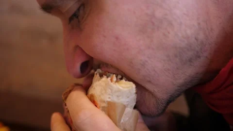 Close-up of a man biting and eating a meat kebab with vegetables in a pita bread Stock Footage 325338725