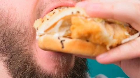 Close up of a man biting a burger on a Chroma Key. The concept of unhealthy and Stock Photos
