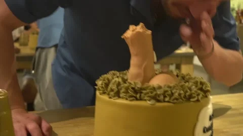 Close-up of a man biting his testicles into a penis-shaped cake for his happy Video stock 194502775