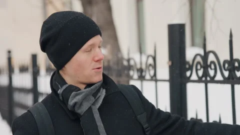 Close up man in black beanie gray scarf standing outdoors snowy urban background Stock Footage 344873538